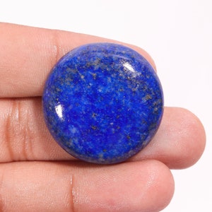 Puede incluir: Un cabujón redondo de lapislázuli pulido, de color azul intenso con motas de pirita dorada.