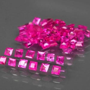 Op de afbeelding: Een stapel roze vierkante edelstenen, met daaronder een rij kleinere roze vierkante edelstenen.