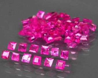 May include: A pile of pink square-shaped gemstones, with a row of smaller pink square-shaped gemstones below.
