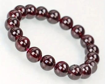 May include: A red gemstone bracelet with round beads. The bracelet is made of natural garnet stones.
