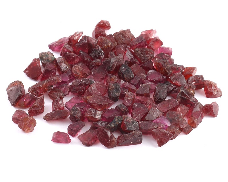 K&ouml;nnte beinhalten: Ein Haufen roher, roter Rubin-Edelsteine. Die Rubinkristalle sind in verschiedenen Gr&ouml;&szlig;en und Formen.
