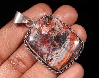 May include: A silver pendant featuring a rectangular, red, white and black agate stone. The stone has a swirling pattern and is set in a silver bezel with a rope-like border.