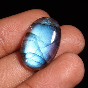 May include: Oval-shaped blue labradorite gemstone with iridescent shimmer and a smooth, polished surface.