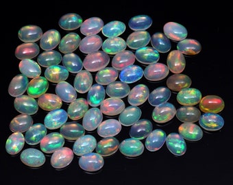 May include: A collection of oval-shaped opal gemstones in various shades of white, green, blue, and pink. The opals are iridescent and have a pearlescent sheen.