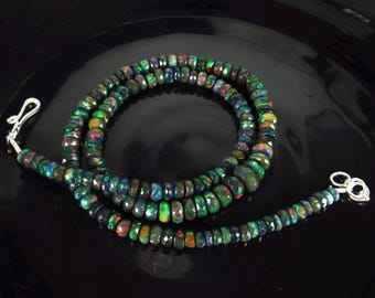 May include: A black and green opal gemstone necklace with silver clasps. The necklace is made of round beads and is approximately 18 inches long.