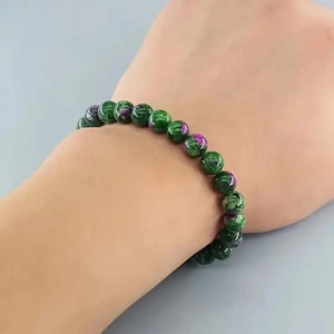 May include: A green and pink gemstone bracelet with round beads.