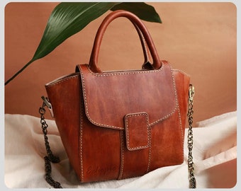Puede incluir: Un bolso de mano de cuero marrón con una correa de cadena y un cierre de solapa. El bolso mide 30 cm de ancho, 20 cm de alto y 10 cm de profundidad. El patrón incluye instrucciones para hacer el bolso.