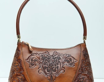 May include: A brown leather handbag with intricate floral carvings. The bag has a single top handle and a zipper closure.