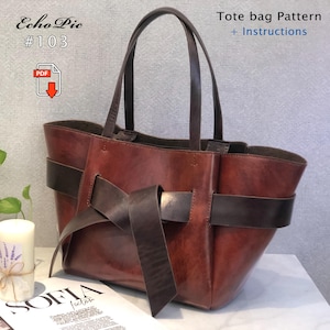 Puede incluir: Un bolso tote de cuero marrón con un detalle de lazo. El bolso tiene dos asas y una correa marrón oscuro que rodea el cuerpo. El texto en la imagen dice "Tote bag Pattern + Instructions" y "Echo Pie #103".