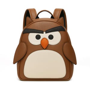 May include: Brown owl-shaped backpack with black, white, and orange accents. The backpack features a top handle, adjustable shoulder straps, and a large front pocket. The owl's face is the focal point, with large white eyes, black eyebrows, and an orange beak.