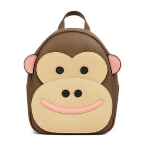 Pode incluir: Mochila marrom com design de rosto de macaco. A mochila apresenta um exterior marrom com um rosto bege claro, olhos pretos e um sorriso rosa. As orelhas são rosa e a mochila tem uma alça superior e dois bolsos laterais.