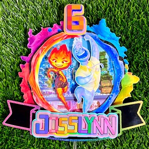 May include: A colorful cake topper featuring characters from the movie "Elemental" with the number 6 and the name "Josslynn" in rainbow letters.