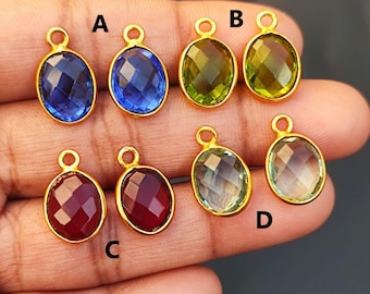 Puede incluir: Seis colgantes ovalados chapados en oro con piedras preciosas de diferentes colores. Los colgantes están etiquetados con A, B, C y D. Las piedras preciosas son azules, verdes y rojas.