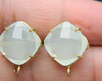 May include: A pair of gold-tone earrings with clear faceted gemstone accents. The earrings have a square shape and a hook closure.