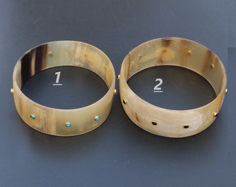May include: Two horn bracelets with gold accents and turquoise stones. The bracelets are numbered 1 and 2.