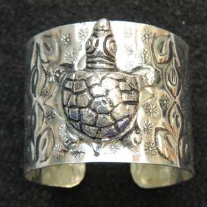 Può includere: Braccialetto in argento con un design in rilievo dettagliato di una tartaruga e motivi floreali.