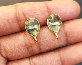 May include: A pair of gold earrings with teardrop-shaped green gemstones.