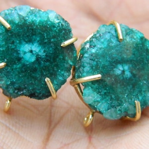 以下が含まれることがあります： 金色のワイヤーセッティングで飾られた緑色の瑪瑙のイヤリングのペア。瑪瑙は、独特のパターンとテクスチャを持つ天然石です。