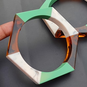 May include: Two hexagonal resin bangles with a green, white, and brown marbled pattern.