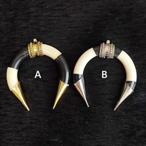 May include: Two crescent-shaped earrings. One has a black and white striped design with a gold-coloured tip and a gold-coloured band. The other has a black and white striped design with a silver-coloured tip and a silver-coloured band.