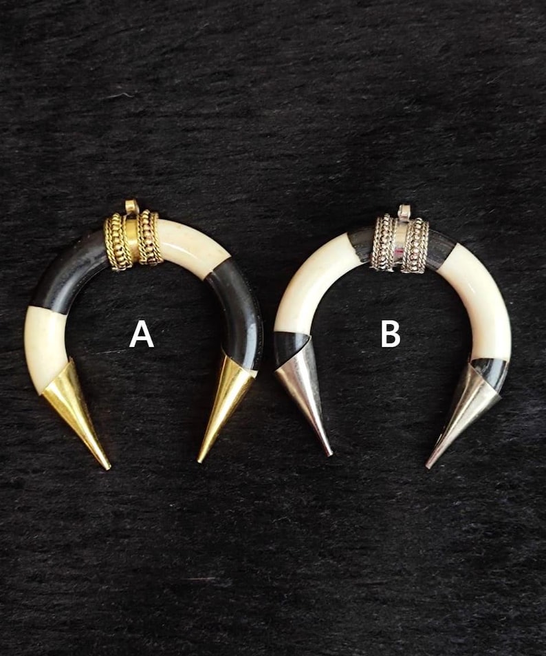 May include: Two horn-shaped earrings. One earring has a black and white striped design with a gold-colored tip and a gold-colored band. The other earring has a black and white striped design with a silver-colored tip and a silver-colored band.