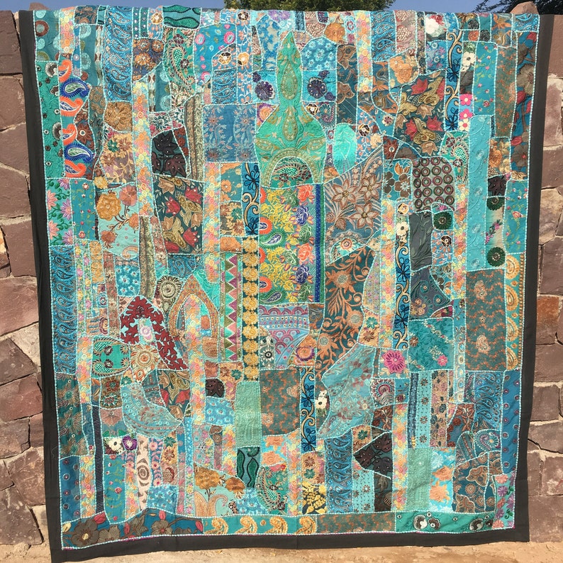 Pode incluir: Uma colcha de retalhos grande e colorida com uma variedade de tecidos e texturas. A colcha &eacute; composta por muitos quadrados e ret&acirc;ngulos diferentes, cada um com um design &uacute;nico. A colcha &eacute; principalmente azul e verde, com acentos de vermelho, laranja, amarelo e roxo.
