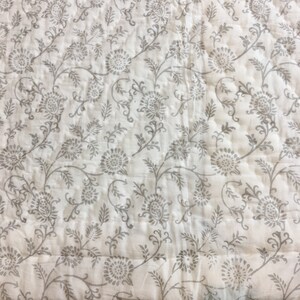 May include: White cotton fabric with a grey floral print. The fabric has a subtle quilted texture.