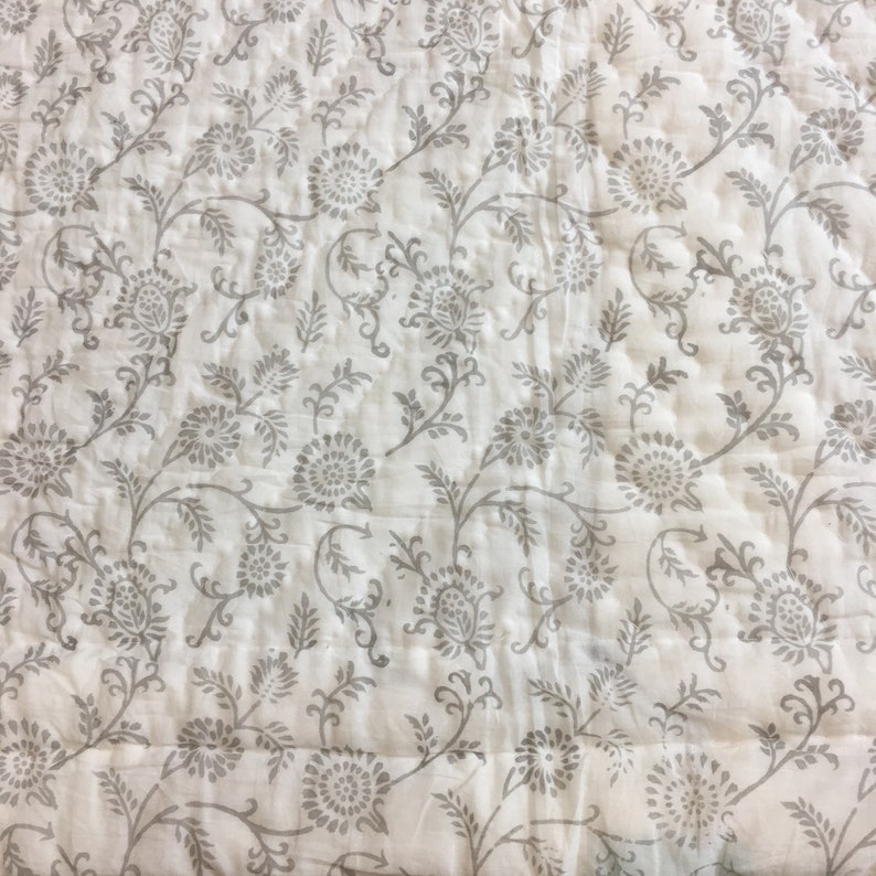 May include: White cotton fabric with a grey floral print. The fabric has a subtle quilted texture.