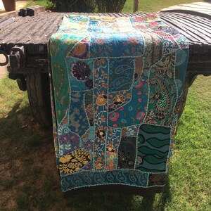 Pode incluir: Uma manta de patchwork azul e verde com bordados intrincados e detalhes de contas. A manta &eacute; feita de v&aacute;rios tecidos e apresenta uma variedade de cores e padr&otilde;es.