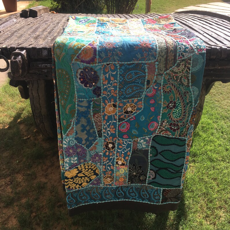 Pode incluir: Uma manta de patchwork azul e verde com bordados intrincados e detalhes de contas. A manta &eacute; feita de v&aacute;rios tecidos e apresenta uma variedade de cores e padr&otilde;es.