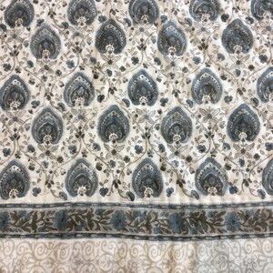 May include: White fabric with a blue and grey paisley pattern. The fabric has a border with a floral design.