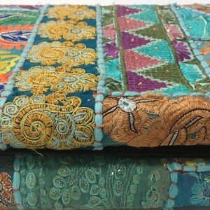 Pode incluir: Um tecido de patchwork colorido com bordados intrincados em tons de azul, verde, amarelo, laranja e rosa. O tecido &eacute; composto por diferentes pe&ccedil;as costuradas juntas, criando um design &uacute;nico e texturizado.