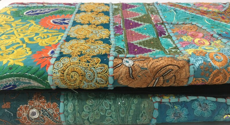 Pode incluir: Um tecido de patchwork colorido com bordados intrincados em tons de azul, verde, amarelo, laranja e rosa. O tecido &eacute; composto por diferentes pe&ccedil;as costuradas juntas, criando um design &uacute;nico e texturizado.