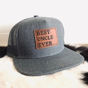 Könnte beinhalten: Eine graue Trucker-Kappe mit einem braunen Leder-Patch, auf dem "BEST. UNCLE. EVER." steht.