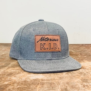 May include: A gray baseball cap with a brown leather patch that says "Notorious K.I.D."