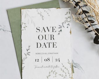 May include: A white rectangular Save the Date card with deckled edges and gold leaf accents, featuring black text that reads SAVE OUR DATE, REBECCA & JONATHAN, 12 | 08 | 24, and Formal invitation to follow, decorated with grey botanical illustrations.