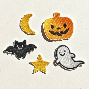 Può includere: Un set di toppe ricamate a tema Halloween. Include una zucca sorridente, una luna crescente, un pipistrello, una stella e un fantasma. Ogni toppa presenta cuciture dettagliate e un bordo bianco, ideale per il fai-da-te.