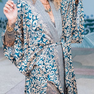 May include: A blue and gold patterned silk robe with a long, flowing design. The robe has a sash tie at the waist and a deep V-neckline.