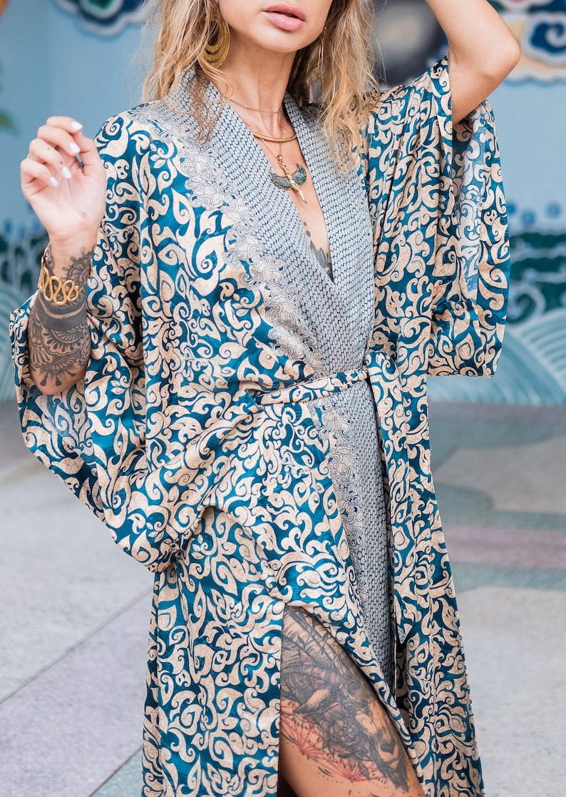 May include: A blue and gold patterned silk robe with a long, flowing design. The robe has a sash tie at the waist and a deep V-neckline.