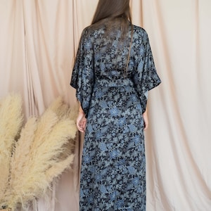 May include: A long, black and blue floral print robe with a sash tie. The robe is made of a soft, silky fabric.