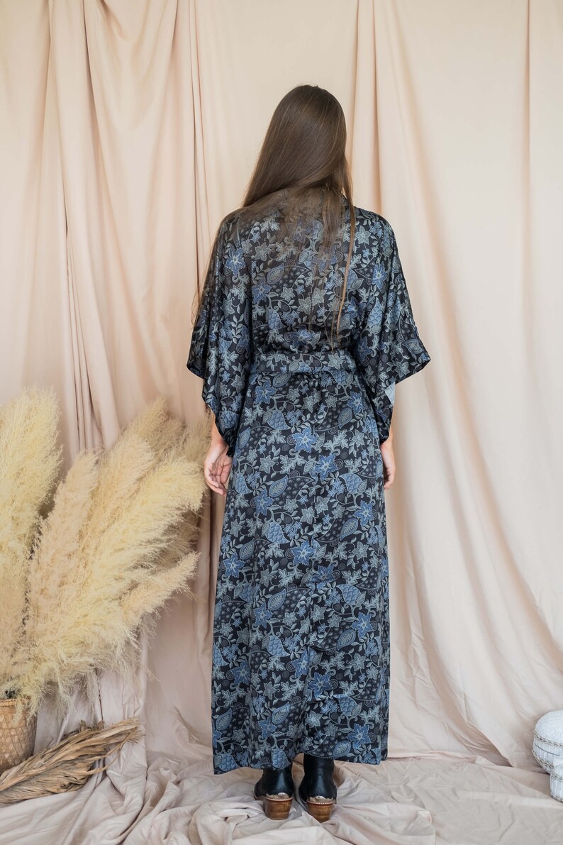 May include: A long, black and blue floral print robe with a sash tie. The robe is made of a soft, silky fabric.