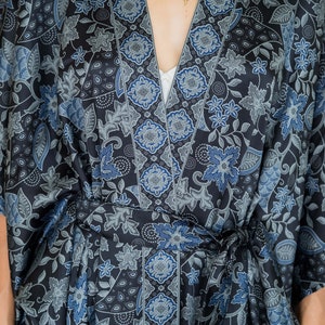 May include: A black and blue patterned silk robe with a tie belt. The robe features a floral design with a geometric border.