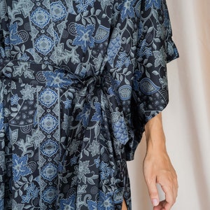 May include: A blue and black floral patterned kimono robe with a sash tie. The robe has a long sleeve and a side slit.