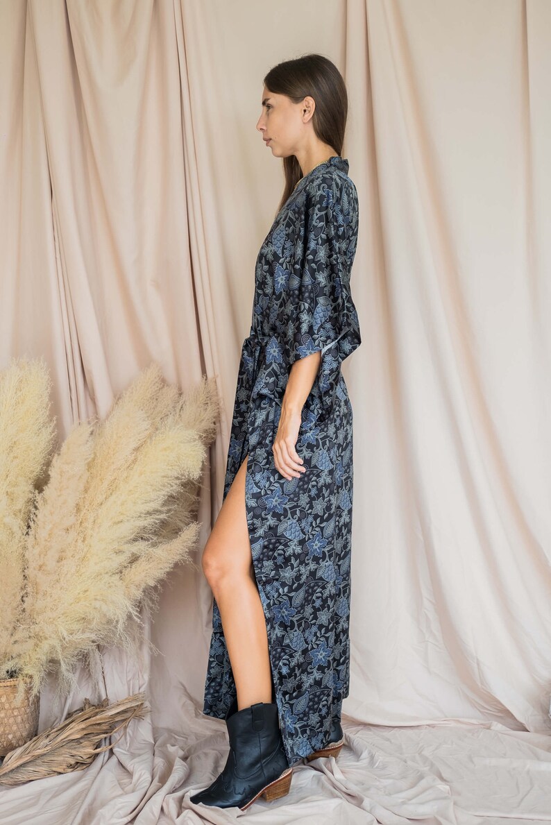 May include: A long, black and blue floral print robe with a side slit and a tie belt. The robe is worn with black ankle boots.