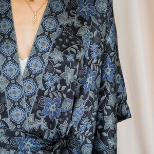 May include: A black and blue floral patterned kimono robe with a long sleeve and a tie belt.