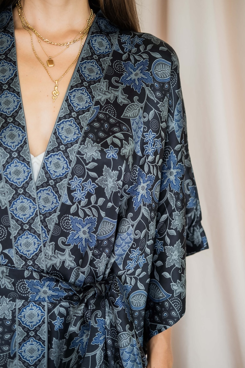 May include: A black and blue floral patterned kimono robe with a long sleeve and a tie belt.