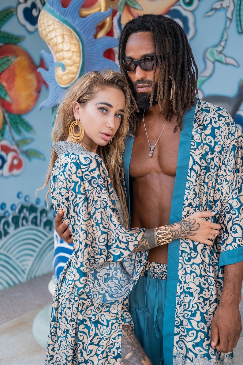 May include: A couple wearing matching blue and cream patterned robes. The woman is wearing large gold hoop earrings. The man has dreadlocks and is wearing sunglasses.