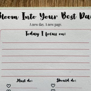 May include: A white ceramic mug with a black handle and the text "But First, Coffee" in a bold, black font. The mug is set against a neutral background, highlighting its simple design.