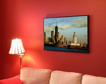 May include: A framed photograph of the Chicago skyline with a lighthouse in the foreground. The photo is in a black frame and is hanging on a red wall.