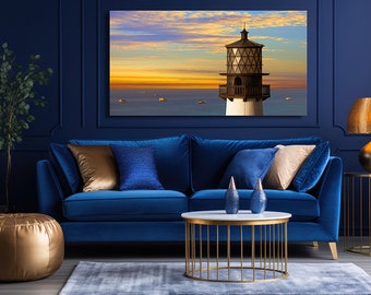 May include: A blue velvet sofa with gold throw pillows sits in a room with a navy blue wall. A gold metal coffee table with a white marble top sits in front of the sofa. A gold lamp with a patterned shade sits on a gold metal side table. A gold pouf sits in the corner of the room. A framed print of a lighthouse at sunset hangs on the wall above the sofa.